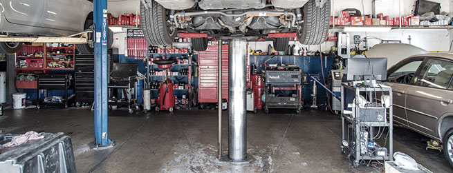 Inside garage of shop, gray car ready for repair, raised up | Quality Tune-Up Auto Care