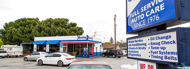 View from outside sign towards the shop, red car parked close to sign | Quality Tune-Up Auto Care