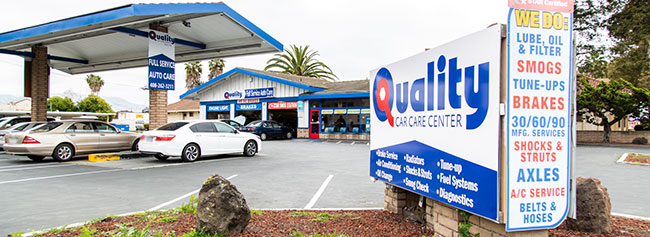 Sign of the shop indicating list of services, with outside of the shop in background and vehicles parked | Quality Tune-Up Auto Care