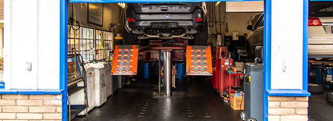 Back view of vehicle in garage ready for repairs, lifted up | Quality Tune-Up Auto Care