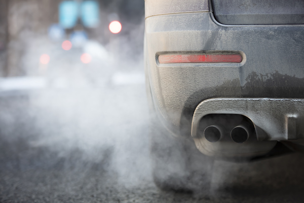 Back view of a dusty vehicle emitting an excessive amount of exhaust